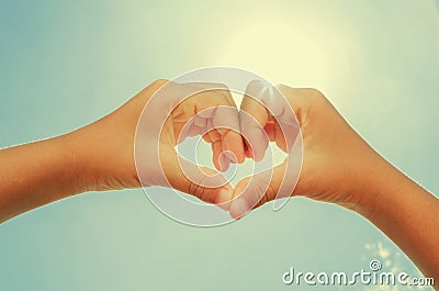 woman forming heart shaped hands with noon sun instagram Stock Photo