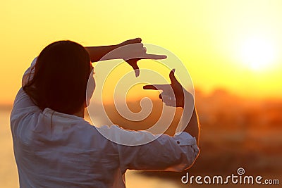 Woman framing with fingers at sunset Stock Photo