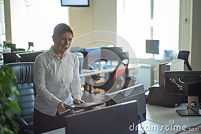 A woman freaks out and gets depressed from a mistake and breaks the keyboard on the monitor. Female manager gets angry Stock Photo