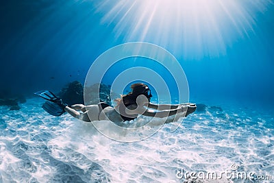 Woman free diver glides with white sand over sandy sea. Freediving underwater in Hawaii Stock Photo