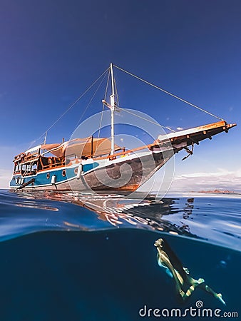 Woman free diving underwater with yacht half view Stock Photo