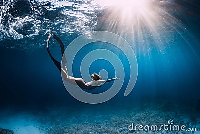 Woman freediver glides with fins. over sandy sea. Freediving and beautiful light in blue sea Stock Photo