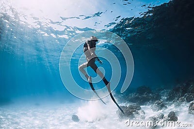 Woman freediver glides over sandy sea with fins. Stock Photo