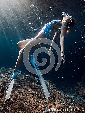 Woman freediver glides underwater in blue sea. Freediving with girl in deep ocean and sun rays Stock Photo