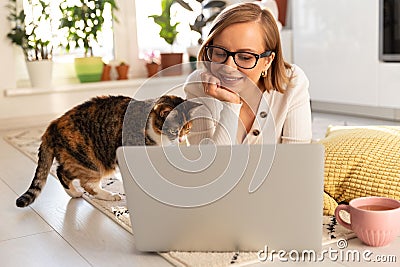 Woman freelancer lies on carpet in living room, watch webinar. Female with her cat talking through video chat with her family who Stock Photo