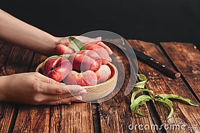 Woman with fresh donut peaches at wooden table, closeup Stock Photo