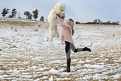 Woman frolicking in the snow with teddy bear Stock Photo