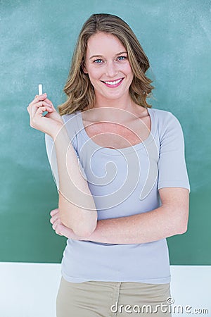 Woman in front of a blackboard holding a piece of chalk Stock Photo