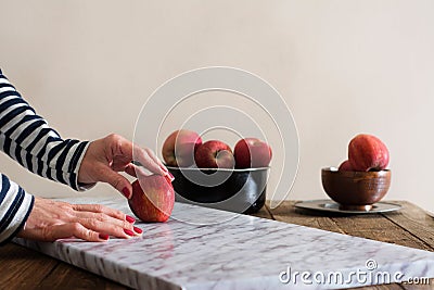 Woman in front of the table with red apple in hand Stock Photo