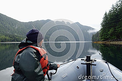 A woman at the front of a zodiac on a tour exploring the ocean, coastlines, forest and islands of Gwaii Haanas, Haida Gwaii Stock Photo