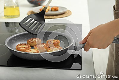 Woman frying delicious cottage cheese pancakes in kitchen, closeup Stock Photo