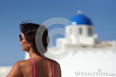 Woman with fuchsia dress and a dome as a background in Oia, Santorini Stock Photo