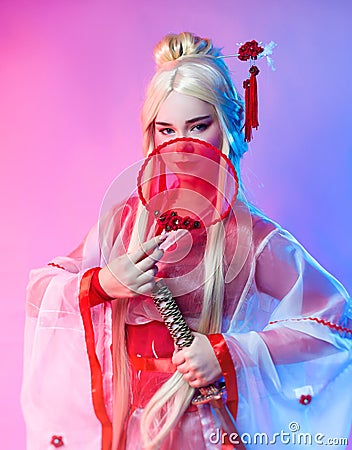 A woman in a geisha costume with a katana and a fan Stock Photo