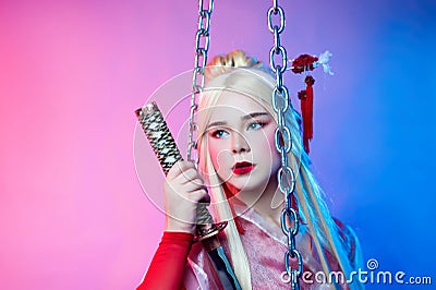 A woman in a geisha costume with a katana next to the chains Stock Photo