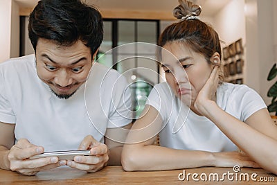 Woman gets bored boyfriend addicted mobile game on their date. Asian couple Stock Photo