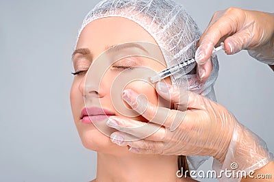 Woman is getting filler injection in cheeks. Anti-aging treatment and face lift. Cosmetic Treatment and Plastic Surgery Stock Photo