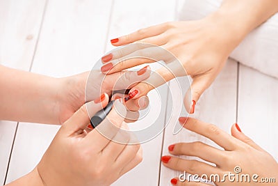 Woman getting nail manicure. Manicurist applying red nail polish to customer Stock Photo