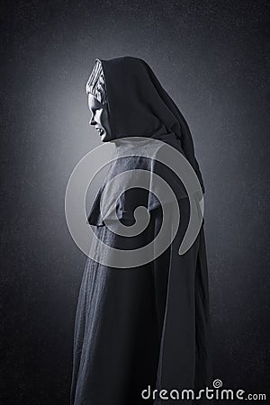 Woman ghost in hooded cloak over dark background Stock Photo