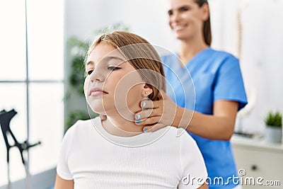 Woman and girl physiotherapist and patient having rehab session massaging neck at physiotherapy clinic Stock Photo