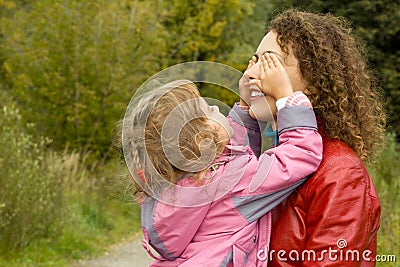 Woman and girl playing in garden, girl closes eyes Stock Photo