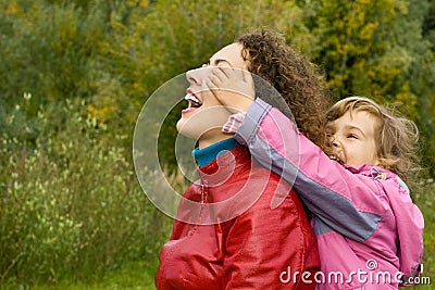 Woman and girl playing in garden, girl closes eyes Stock Photo
