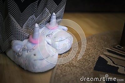 Woman or a girl wearing a cute plush fluffy slippers made in the form of unicorn Stock Photo