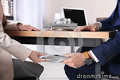 Woman giving bribe to man under table in office Stock Photo