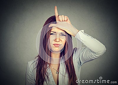 Woman giving loser sign looking at you with disgust on face Stock Photo