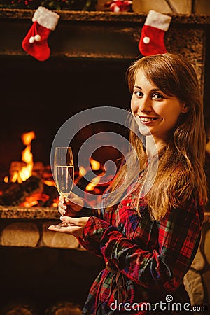 Woman with a glass of champagne by the fireplace. Young woman si Stock Photo