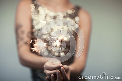 Woman in glitter dress holding sparkler, close up hands, romantic look Stock Photo