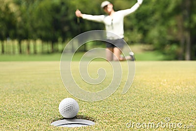 Woman golfer cheering after a golf ball on green Stock Photo