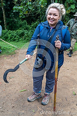 Woman on a gorilla trek in Uganda holds a machete in prepration for her hike to see mountain gorillas Stock Photo