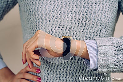 Woman in a gray sweater checks the time on a wrist watch close-up Stock Photo