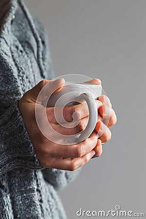 Woman wearing gray woolly cardigan holding warm cup of tea Stock Photo