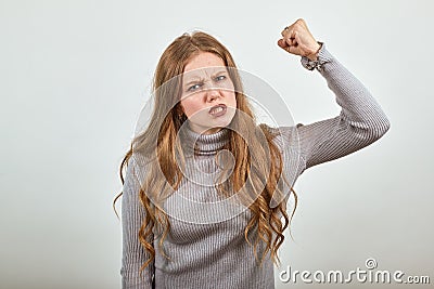 Woman in gray sweater an irritated angry lady shakes her fist in anger Stock Photo