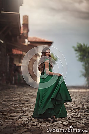 Woman in green dress on the streets of the old town. Young tourist on vacation travel smiling happy walking joyful in Stock Photo