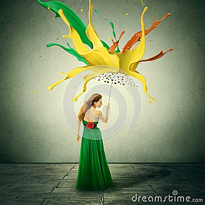 Woman in green dress with umbrella as shelter against colorful drops splashes of paint falling down Stock Photo