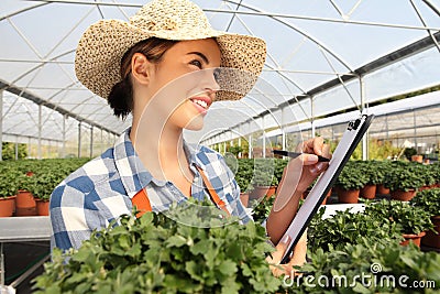 Woman in the greenhouse to take notes on the clipboard Stock Photo