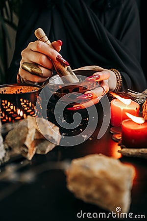 A woman grinds dried plants in a wooden mortar Stock Photo