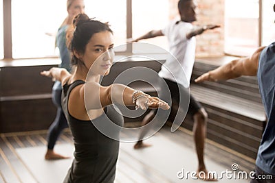 Woman and a group of sporty people in Warrior two Stock Photo