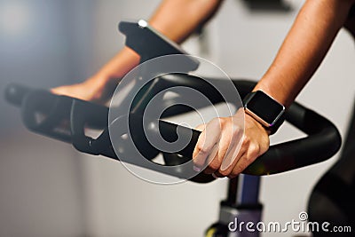 Woman at a gym doing spinning or cyclo indoor with smart watch Stock Photo