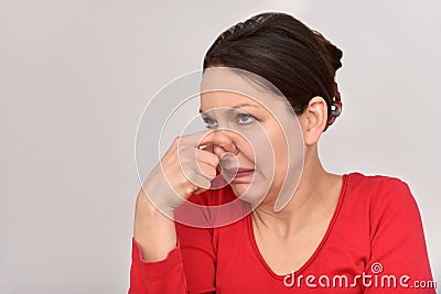 Woman with hair bun holding her nose Stock Photo