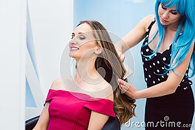 Woman hairdresser styling hair of customer in her shop Stock Photo