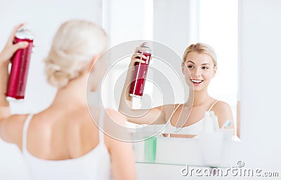 Woman with hairspray styling her hair at bathroom Stock Photo