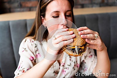 Woman hamburger eat. Hungry Caucasian Female Eating Tasty Burger. Fast food, people and unhealthy eating concept. Stock Photo