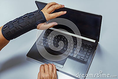 Woman hand in black orthosis is closes computer after work Stock Photo