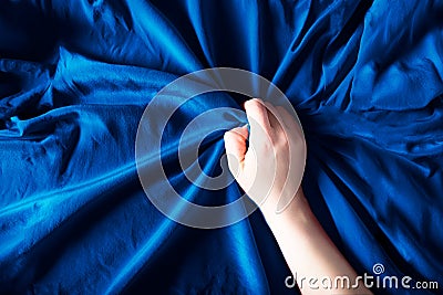 Woman hand on blue silk bedding, sex and orgasm concept Stock Photo