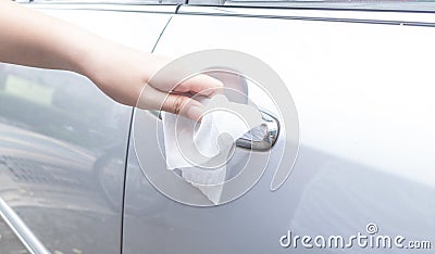 Woman hand cleaning removing germs with antibacterial wet wipes on car door handle for corona virus COVID-19 Stock Photo