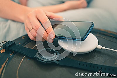 woman hand close up putting phone on wireless charger Stock Photo