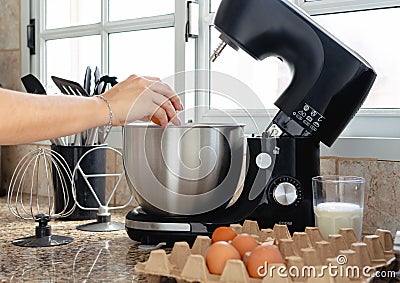 Woman hand cracking an egg inside mixer bowl for making a cake Stock Photo